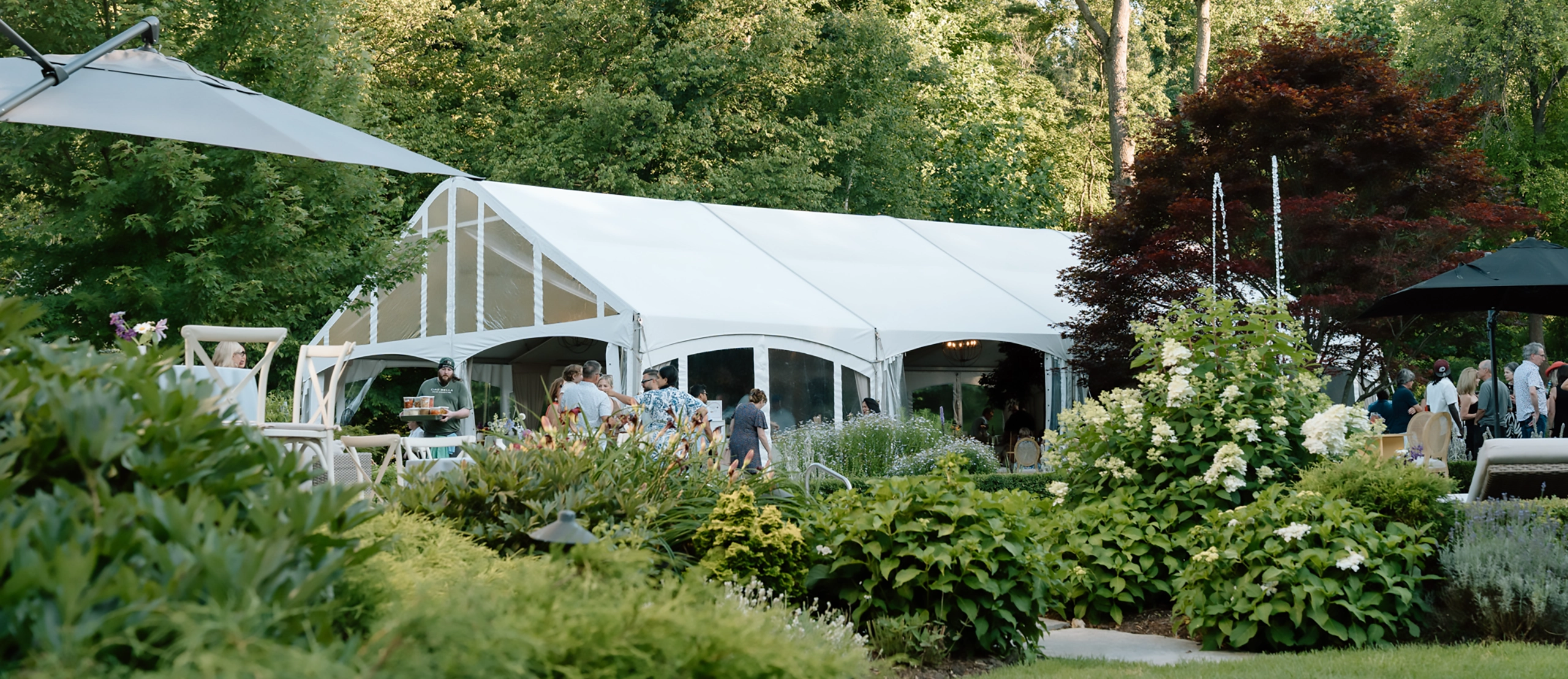 Anniversary event setup outdoors with lots of people and legacy tent in background
