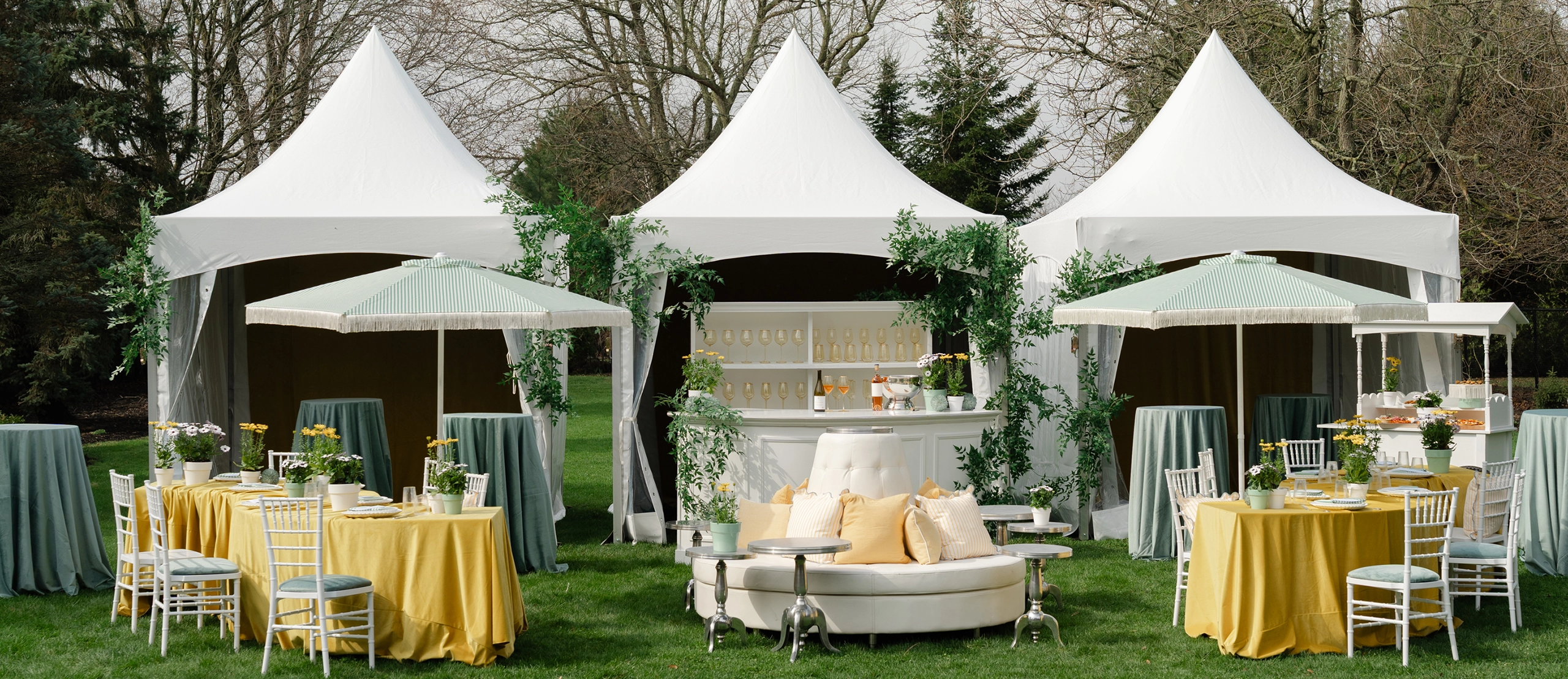 Three high-peak tents in a row, making up a cocktail area at an outdoor event