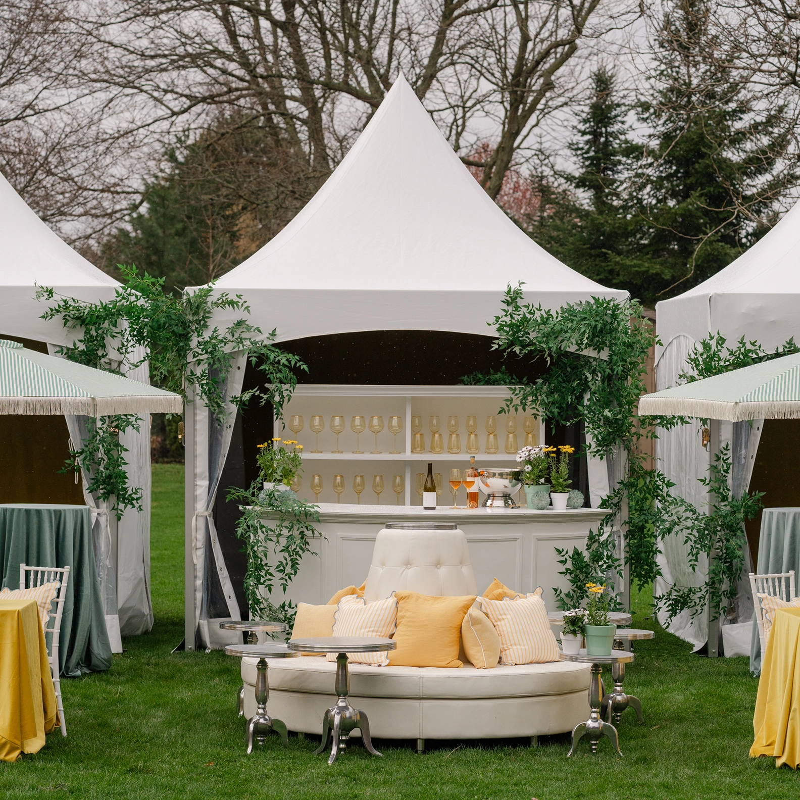 White circular lounge sofa with light yellow throw pillows in front of a wine bar located in a High-Peak tent